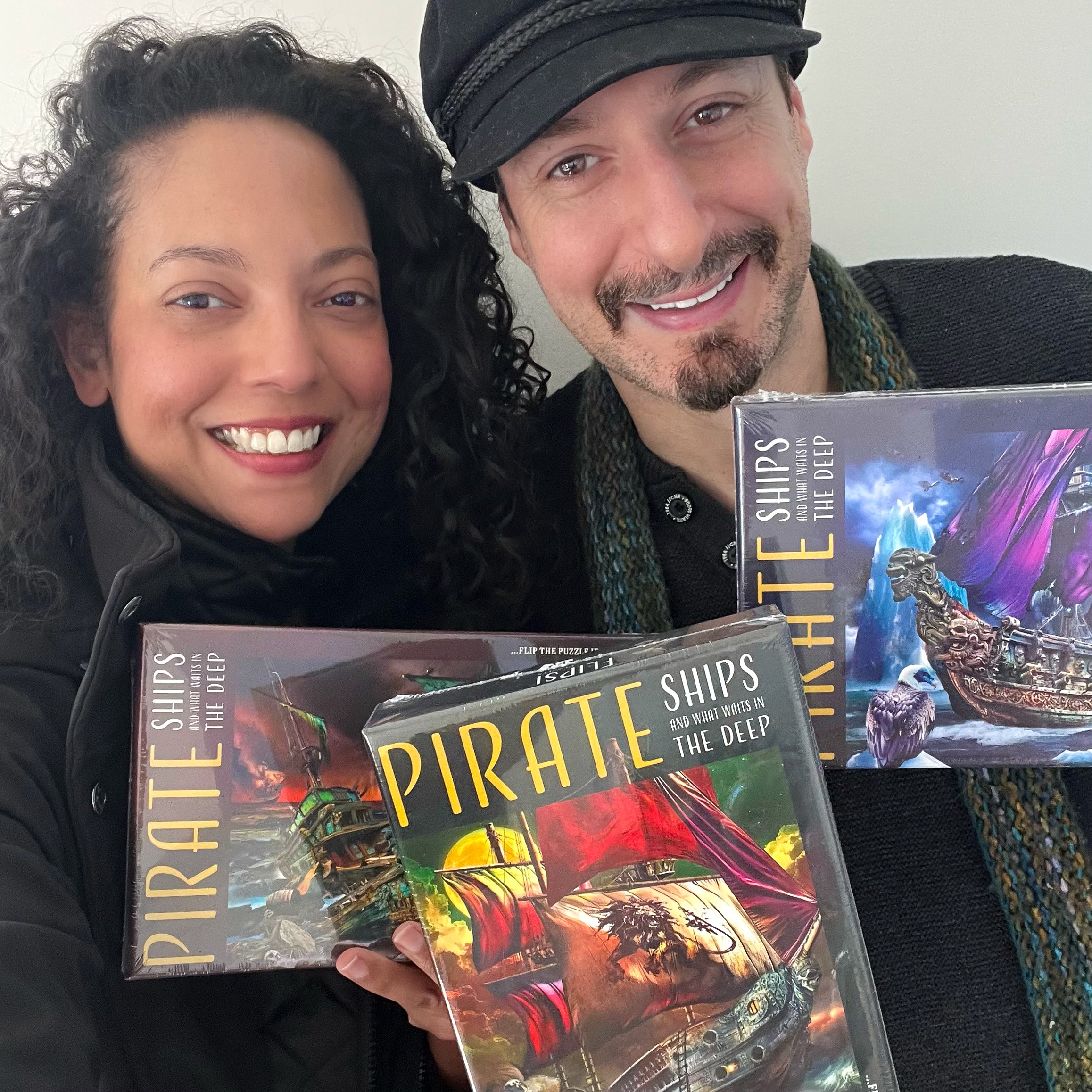 Melissa and Demi smiling and holding three Pirate Ships Flipsi puzzle boxes.